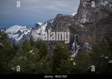 Yosemite innevato paesaggio con crollo Cascate di Bridalveil e mezza cupola della faccia di granito. Foto Stock