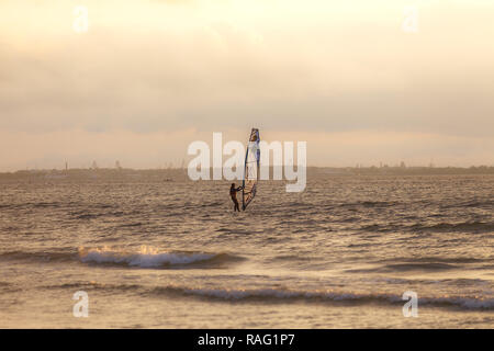 TALLINN, Estonia - Agosto 10, 2017: Sportman windsurf sulla superficie del mare contro il tramonto cielo arancione Foto Stock