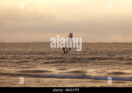 TALLINN, Estonia - Agosto 10, 2017: Sportman windsurf sulla superficie del mare contro il tramonto cielo arancione Foto Stock