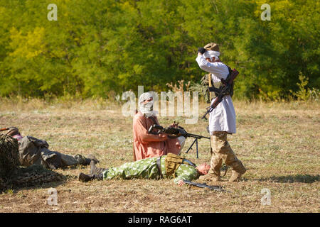 Festival storici Sambek altezze. Mujahideen sul campo di battaglia tra i morti soldati sovietici Foto Stock