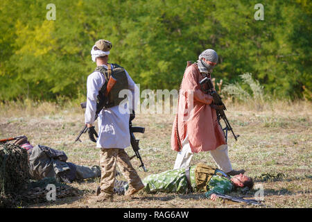 Festival storici Sambek altezze. Mujahideen sul campo di battaglia tra i morti soldati sovietici Foto Stock