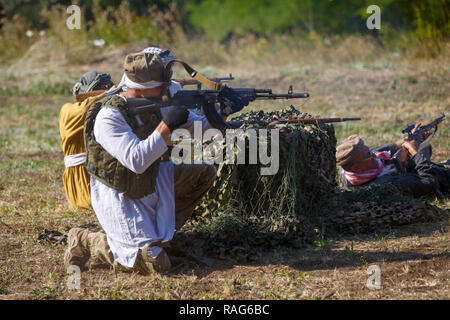 Festival storici Sambek altezze. Mujahideen sparare da dietro il coperchio Foto Stock