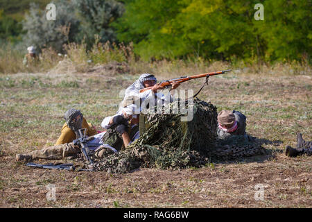 Festival storici Sambek altezze. Mujahideen sparare da dietro le scatole di arma Foto Stock