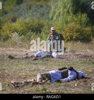 Festival storici Sambek altezze. Soldato sovietico con una pistola in mano contro lo sfondo dell'assassinato Mujahideen Foto Stock