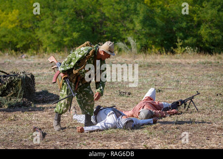 Festival storici Sambek altezze. Soldato sovietico con una mitragliatrice nelle sue mani si appoggia su un punto morto mojahed Foto Stock