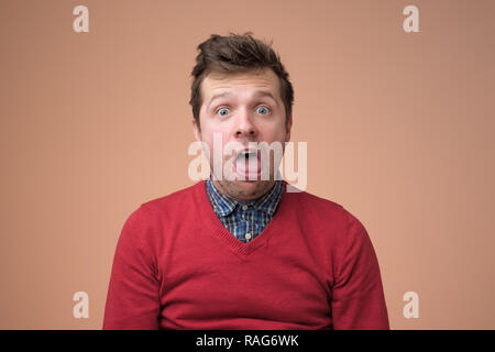 Giovani funny man in camicia bianca, gesticolando scioccato o espressioni di sorpresa con la bocca aperta Foto Stock