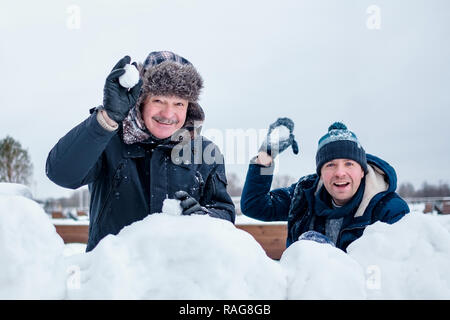 Un uomo anziano e il suo giovane figlio di gettare una palla di neve, Foto Stock