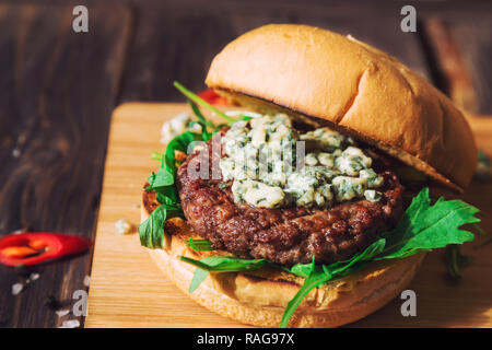 Fresh burger con formaggio blu e rucola su rustico sfondo di legno Foto Stock