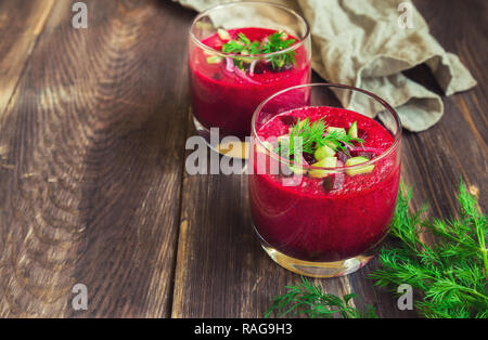 La barbabietola rossa gazpacho zuppa di cetriolo e aneto in bicchieri sul rustico sfondo di legno Foto Stock