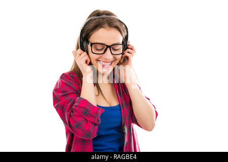 Felice adolescente in abito casual e bicchieri utilizzando le cuffie e ascolto di brani musicali su sfondo bianco Foto Stock