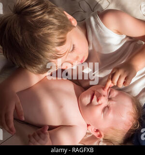 Fratello maggiore è in corso di riproduzione con il neonato. Carino boy amorevolmente giocando con il suo bambino sorella. Il concetto di amore e di amicizia tra vecchi e younge Foto Stock