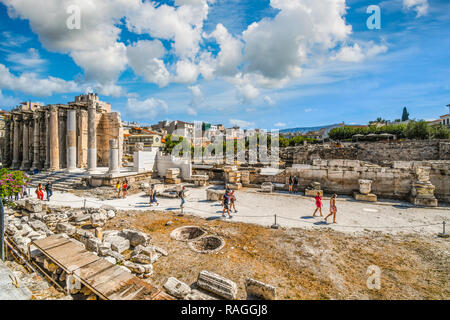 I turisti passeggiata all'antica parete ovest di Adriano della biblioteca presso il romano Agora, con il famoso quartiere Plaka dietro, ad Atene, in Grecia. Foto Stock