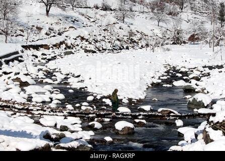 Anantnag, India. Xiv Feb, 2018. Una signora del Kashmir attraversando ponte di legno durante la nevicata a Pahalgam su Gennaio 3, 2019 a circa 100 chilometri da Srinagar, India. Il Kashmir ha ricevuto la sua prima nevicata del nuovo anno la rottura di un mese-lungo periodo di siccità nella valle. Credito: Aasif Shafi/Pacific Press/Alamy Live News Foto Stock