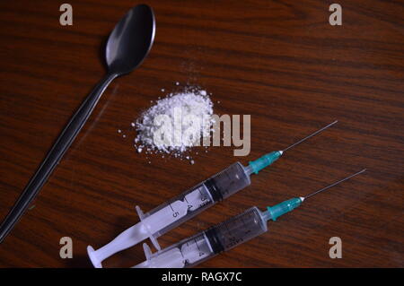 Narcotici essendo preparato. Aghi, cucchiaio e polvere bianca su una tabella. Foto Stock