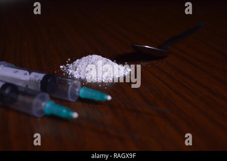 Narcotici essendo preparato. Aghi, cucchiaio e polvere bianca su una tabella. Foto Stock