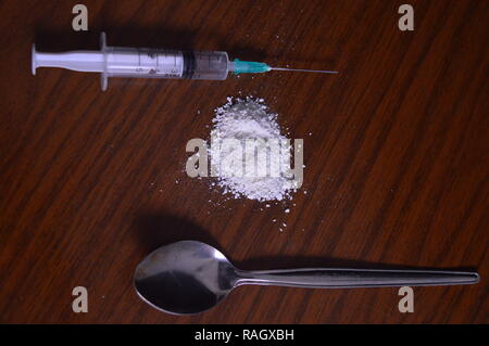 Narcotici essendo preparato. Aghi, cucchiaio e polvere bianca su una tabella. Foto Stock