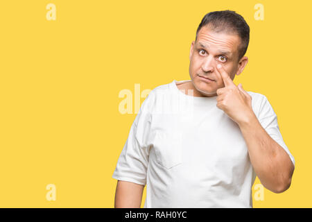 La mezza età uomo arabo wearig t-shirt bianco su sfondo isolata rivolta verso l'occhio ti guarda gesto, espressione sospette Foto Stock