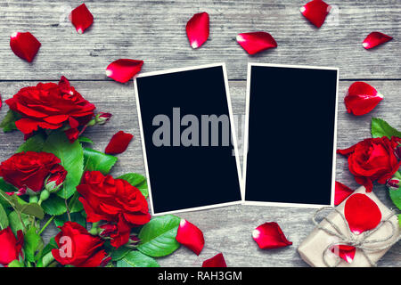 Il giorno di san valentino sfondo. Fustellato cornici fotografiche con red rose bouquet di fiori e scatola regalo in legno rustico sfondo. vista dall'alto. mock up. laici piatta Foto Stock