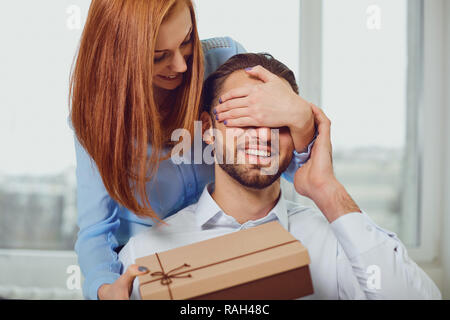 Il giovane dà un dono con i suoi occhi chiusi in camera . Foto Stock