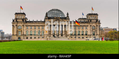 Edificio del Reichstag del parlamento tedesco a Berlino, tedesco bandiere che sventolano al di sopra del punto di riferimento della capitale tedesca Foto Stock