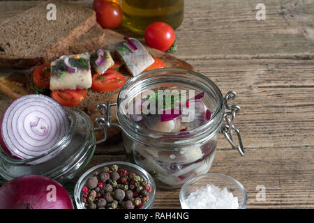 In casa decapati filetti di aringhe in un vaso e panini con le aringhe e pomodori per la prima colazione. close up Foto Stock