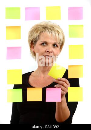 Donna PostIt incollaggio note adesive per una lastra di vetro Foto Stock