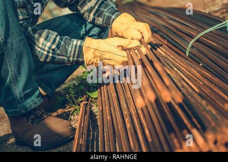 Industria edile. Anima di rinforzo di acciaio barre su un terreno. I contraenti le mani su elementi in acciaio. Foto Stock