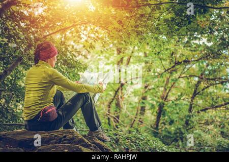 Escursionista femmina con mappa locale in mani cercando la prossima destinazione. Viaggi e ricreazione tema. Foto Stock