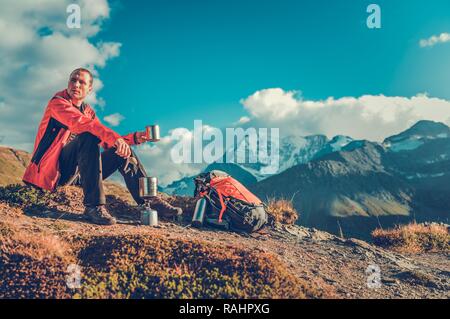 Bevanda calda su un sentiero. Backpacker caucasica nel suo 30s tenendo Short Break e godendo di tè caldo. Foto Stock