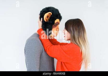 Divertente coppia giovane, ragazzo che indossa la maschera di scimmia, pazzo idiota e rapporto di amore Foto Stock