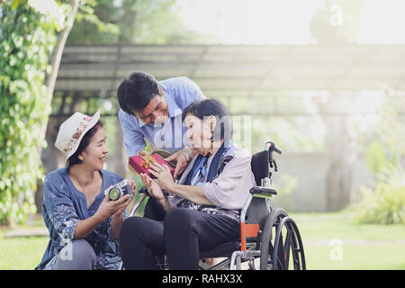 Il figlio e la nuora dono madre anziana in cortile Foto Stock