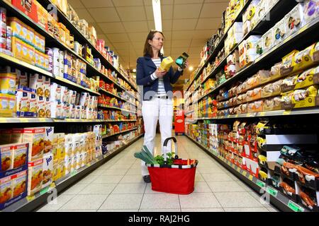 Donna acquisto di farina e il lievito ingredienti in un self-service di reparto drogheria, supermercato Foto Stock