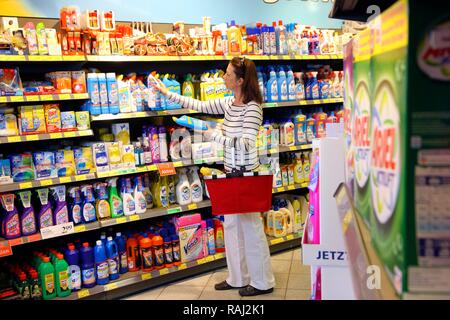 Donna che guarda i prodotti di pulizia in un corridoio con beni domestici mentre lo shopping in un self-service department di negozi di generi alimentari Foto Stock