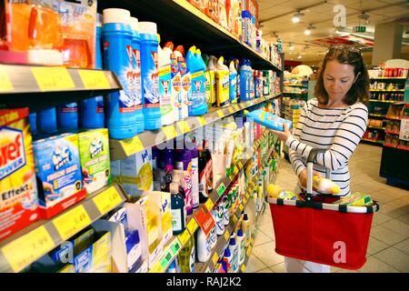 Donna che guarda i prodotti di pulizia in un corridoio con beni domestici mentre lo shopping in un self-service department di negozi di generi alimentari Foto Stock