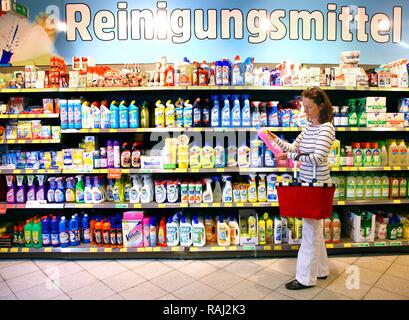 Donna che guarda i prodotti di pulizia in un corridoio con beni domestici mentre lo shopping in un self-service department di negozi di generi alimentari Foto Stock