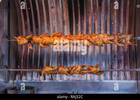 Piccoli polli tostatura in una macchina rotissarie, ad Istanbul in Turchia. Foto Stock