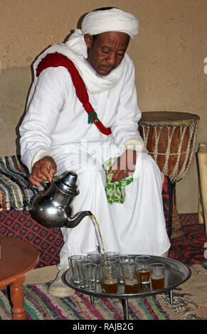 Gnawa uomo tribale in Khamlia, Merzouga che serve tè in Marocco tradizionale cerimonia del tè Foto Stock
