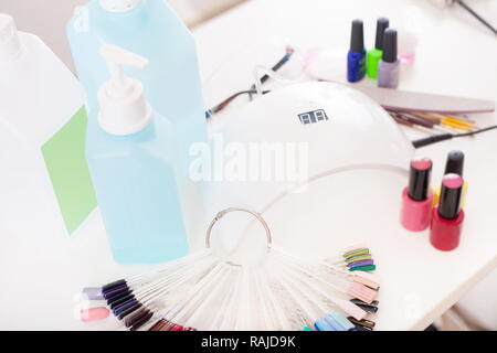 Manicure Set per unghie gel procedura - Nail lampada LED, colori lucidi per gel, disinfettanti e altri accessori sul tavolo bianco. Foto Stock