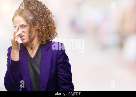 Bruna giovane studente bambina indossa uniformi scolastiche e bicchieri su sfondo isolato annusare qualcosa di maleodorante e disgustoso, intollerabile odore, h Foto Stock