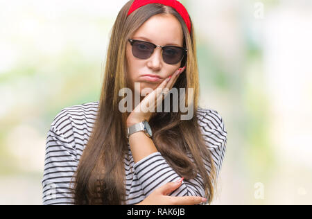 Giovani caucasici bella donna che indossa gli occhiali da sole su sfondo isolato pensare guardando stanco ed annoiato con depressione problemi con braccio incrociato Foto Stock