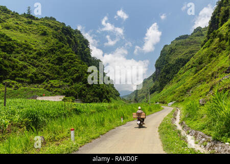 Uomo in sella alla sua moto su una strada di montagna, portante un pacchetto. Ha Giang Loop, Ha Giang Provincia, Vietnam Asia Foto Stock