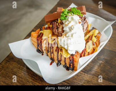 Il miele santos gelato dessert / pane con gelato al cioccolato palline di corn flake montare la panna barra di cioccolato e miele delle api su piastra bianca in cafe co Foto Stock