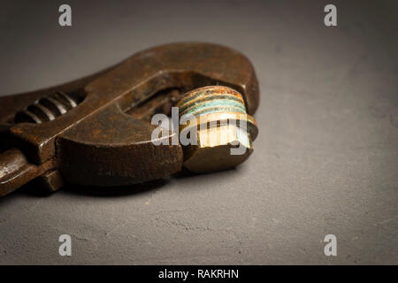 Close up vintage rusty chiave regolabile al buio su un superficie di cemento. Plumbing DIY concetto di riparazione Foto Stock