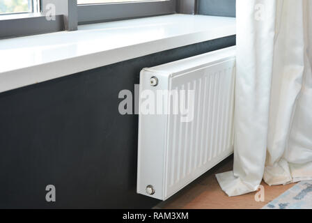 White radiatore riscaldamento con termostato per il risparmio di energia nella camera da letto di lusso con le pareti nere e whitesun cieco. Foto Stock
