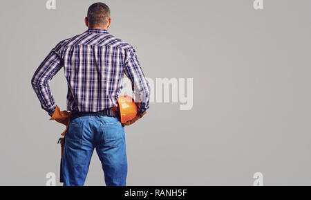 Un costruttore di uomo con un casco nelle sue mani vista posteriore Foto Stock