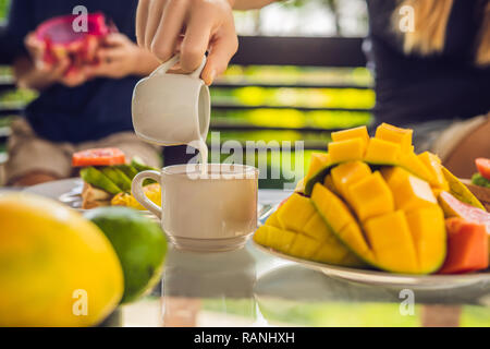 Il momento versando il latte nel caffè. Donna versando la crema di caffè Foto Stock