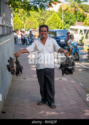 Ragazzo indonesiano sorridente e mostrando il pollo in mani Foto Stock