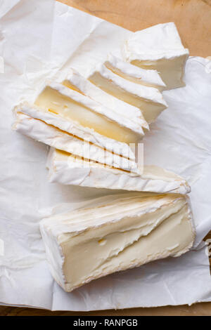 Close up di fettine di soft bianca la crosta del formaggio sul tagliere di legno Foto Stock