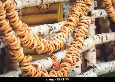 Bagel in un mazzetto appendere su una tavola di legno di betulla, recinto da un tradizionale russo trattare Foto Stock
