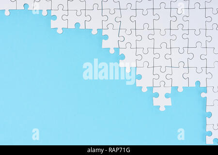 Lay piatto bianco con pezzi di un puzzle su sfondo blu Foto Stock